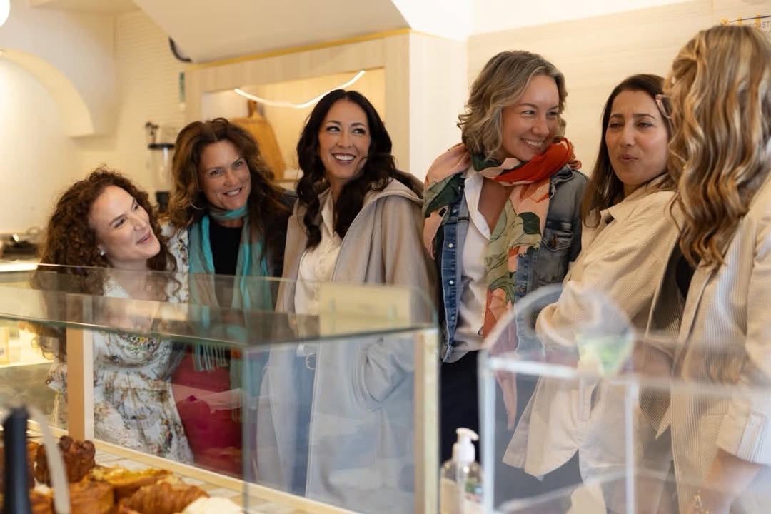 Amy laughing with a group of women at a bakery counter